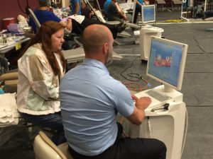 A dentist looks at images of a patient's teeth with her during the 2016 Colorado Mission of Mercy.